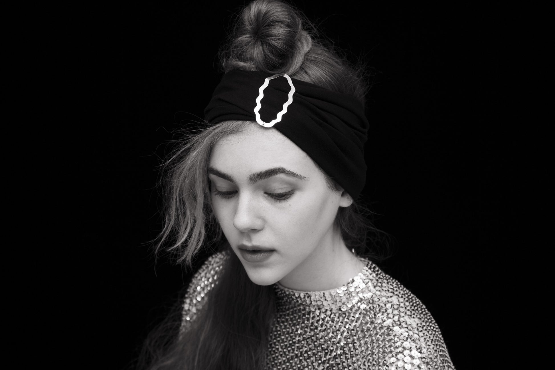 Model wearing her hair in a top knot styled with a headband and accessorized with designer hair clip Helia
