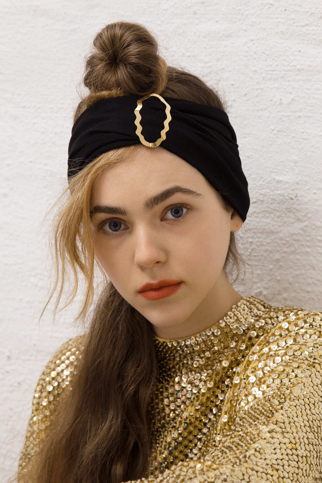Portrait of model wearing her hair in a top knot with a headband accessorized with designer hair clip Helia