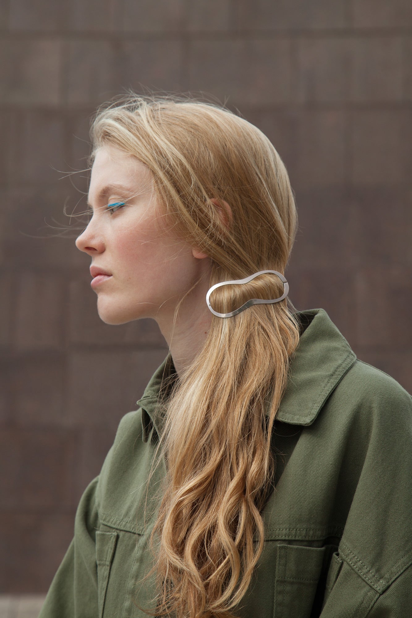 Model looking to be side wearing her hair in a low messy ponytail styled with designer hair clip Elif