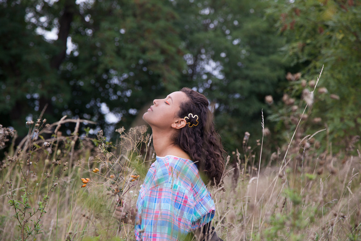 Model looking up with her curly hair down accented with designer hair clip Hilma