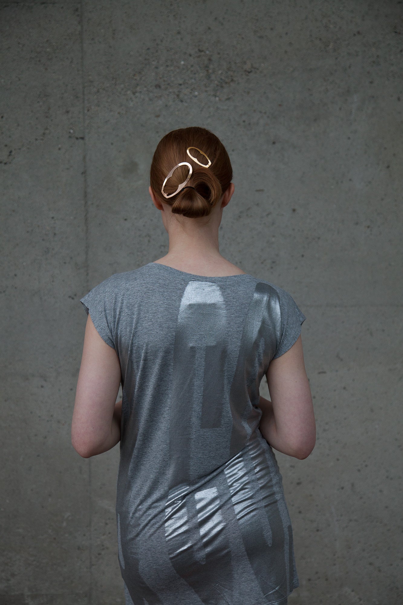 Back view of model wearing her hair in a folded low ponytail styled with designer hair jewelry Enid and Jane