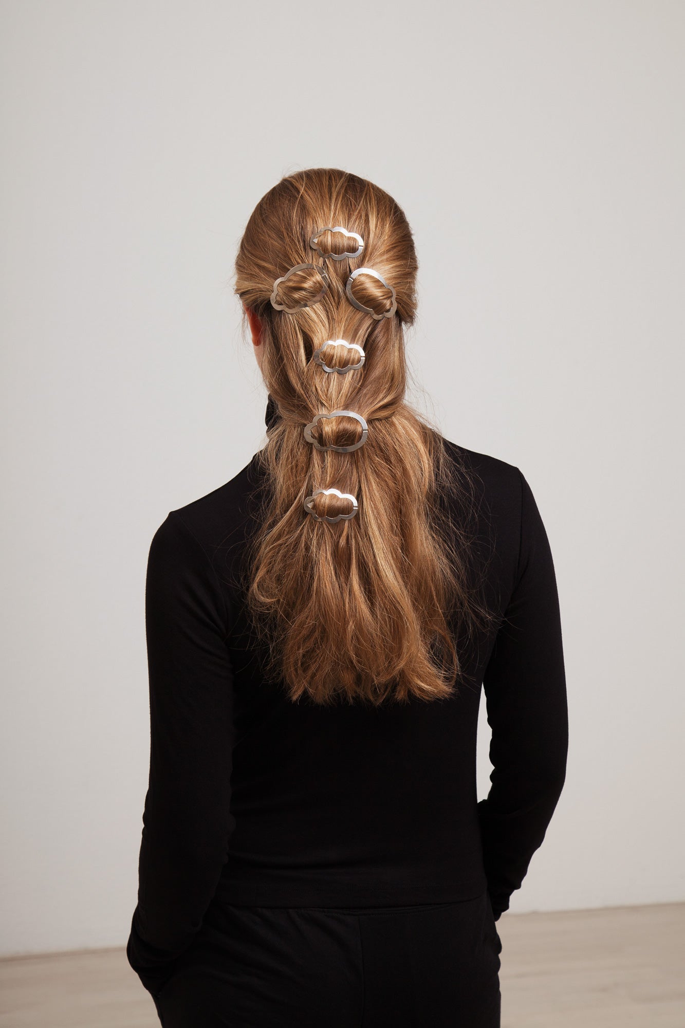 Back view of model wearing her long hair in a half updo styled with designer hair clips Camille and Louise by Clinq