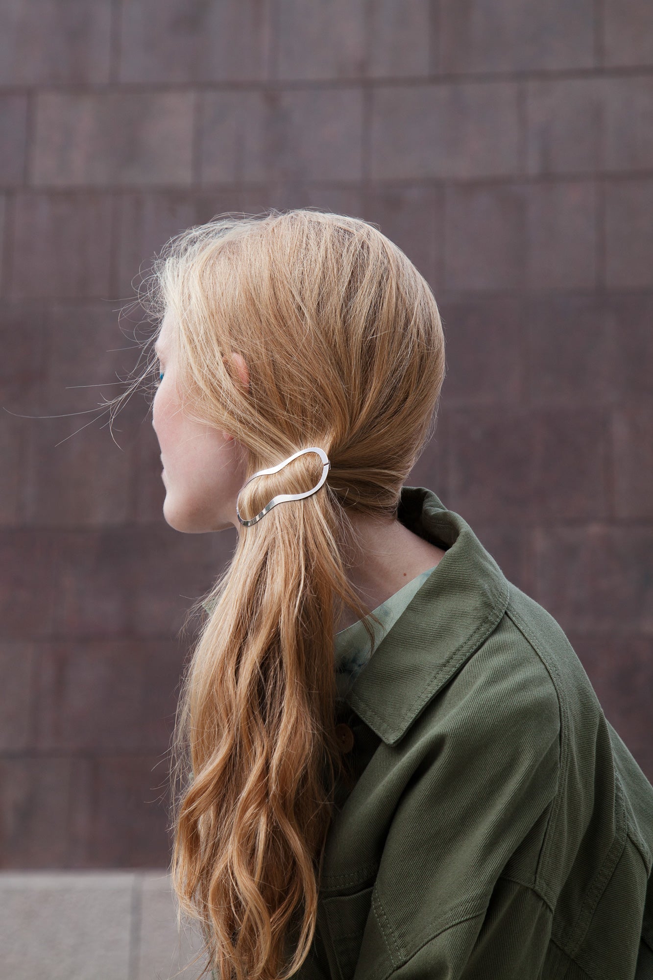 Side view of model wearing her hair in a low messy ponytail secured with designer barrette Elif by Clinq