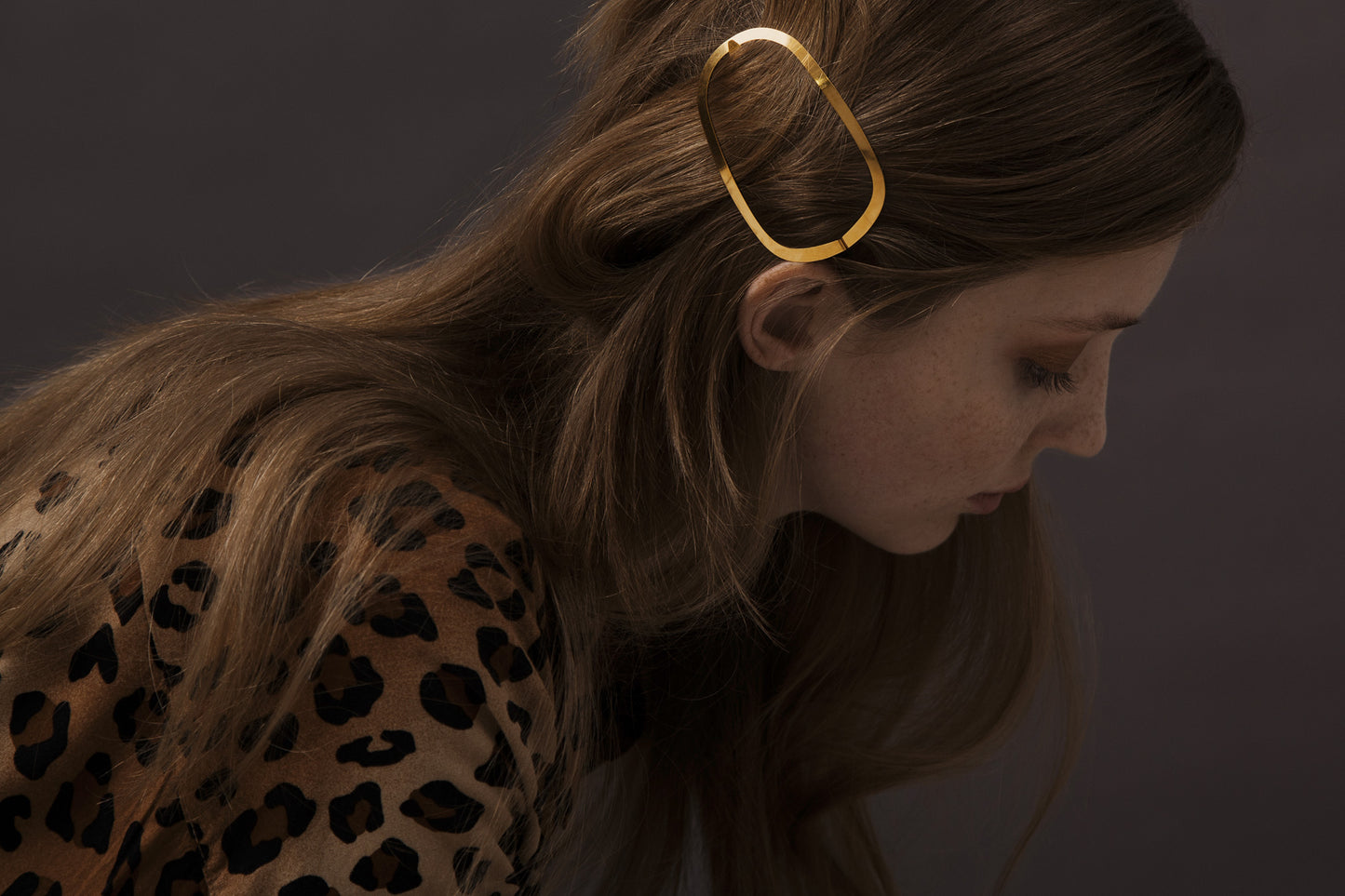Model looking down with her hair accented with designer hair clip Ginger by Clinq in gold-plated