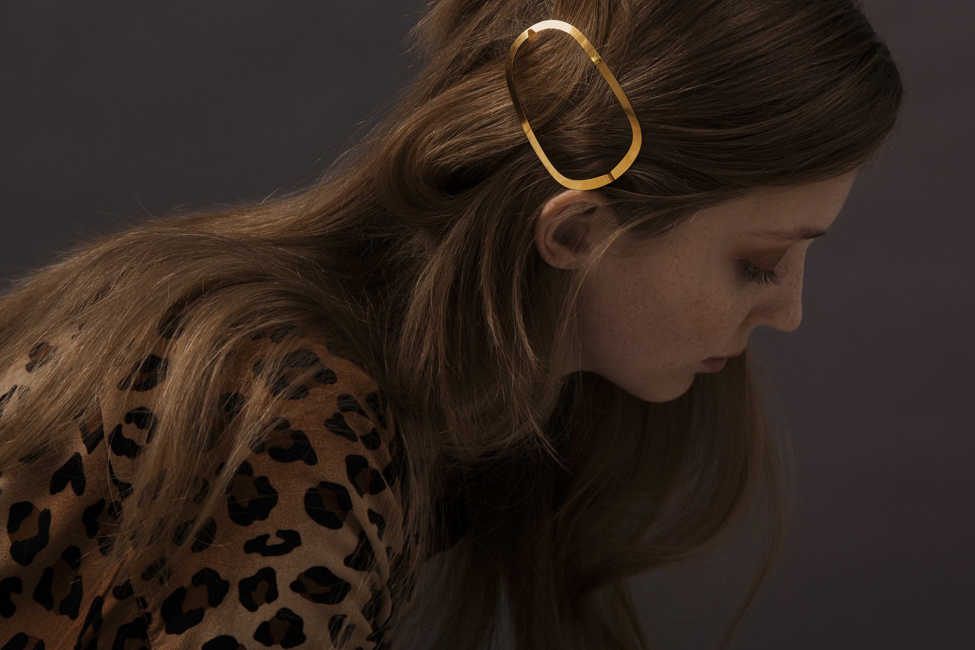 Model looking down with her hair accented with designer hair clip Ginger by Clinq in gold-plated