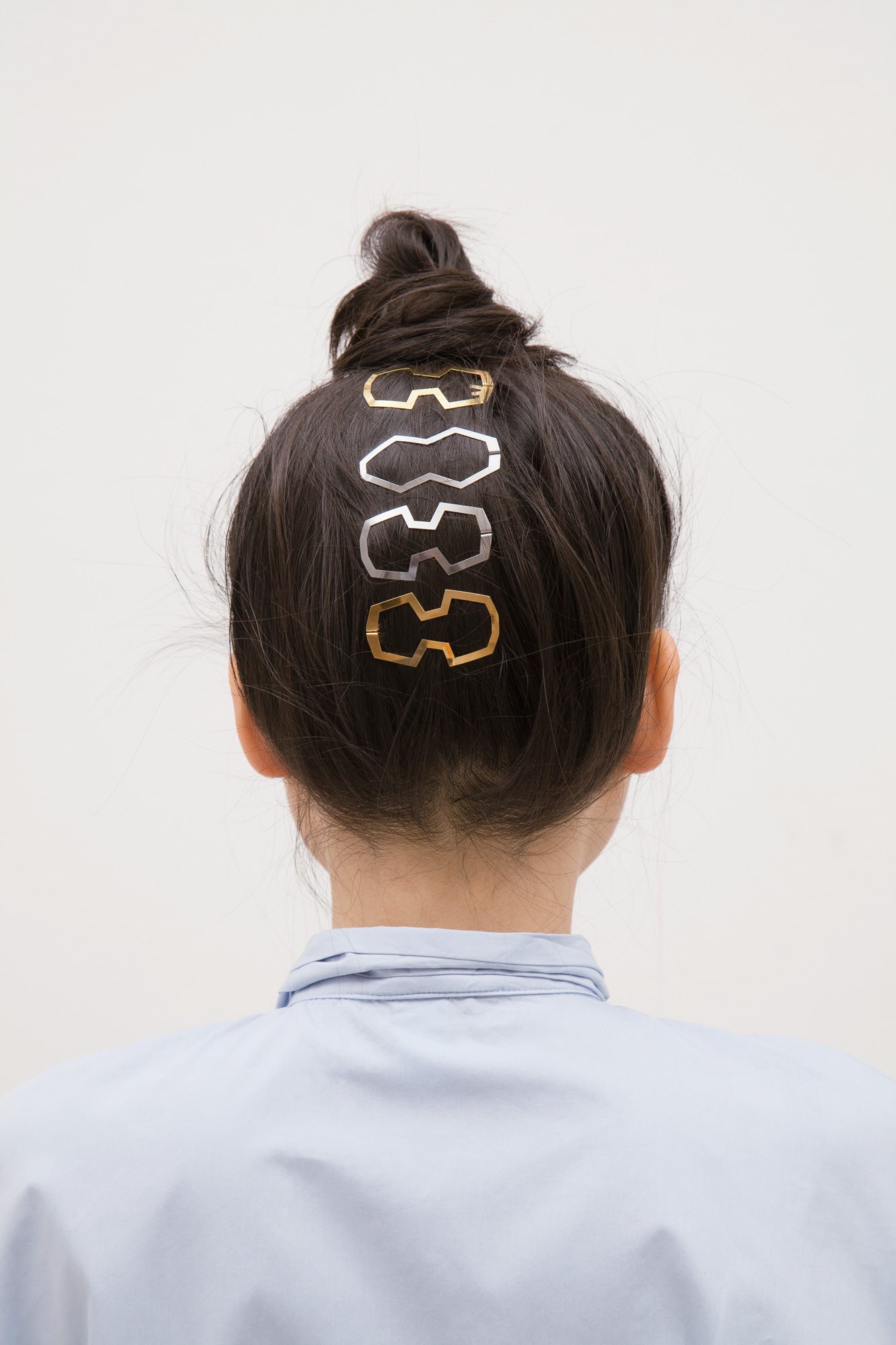 Model wearing a top knot with several designer hair clips by CLINQ