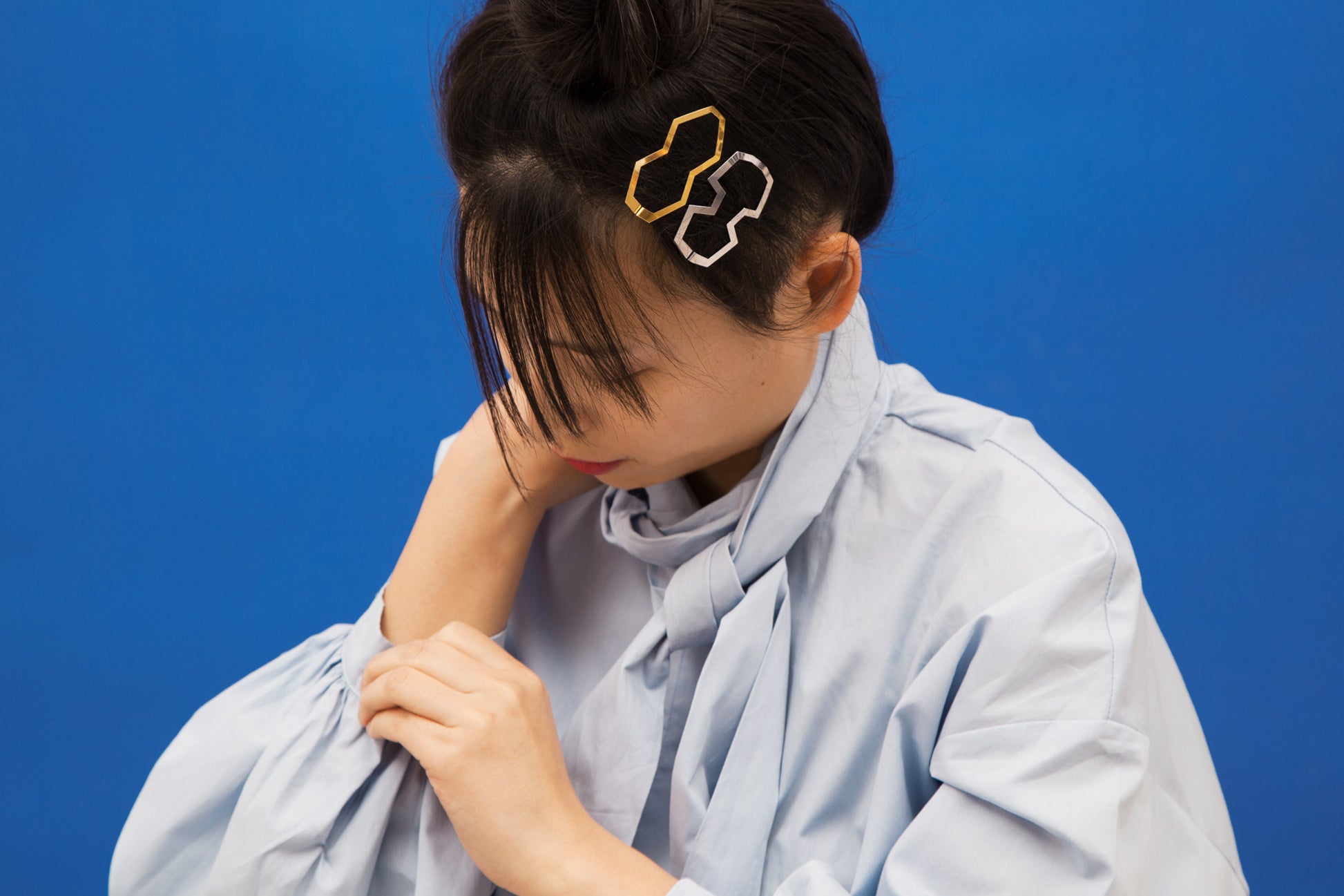 Model wearing a top knot with designer barrettes BIA and MARIE by CLINQ as decorative accents on the side