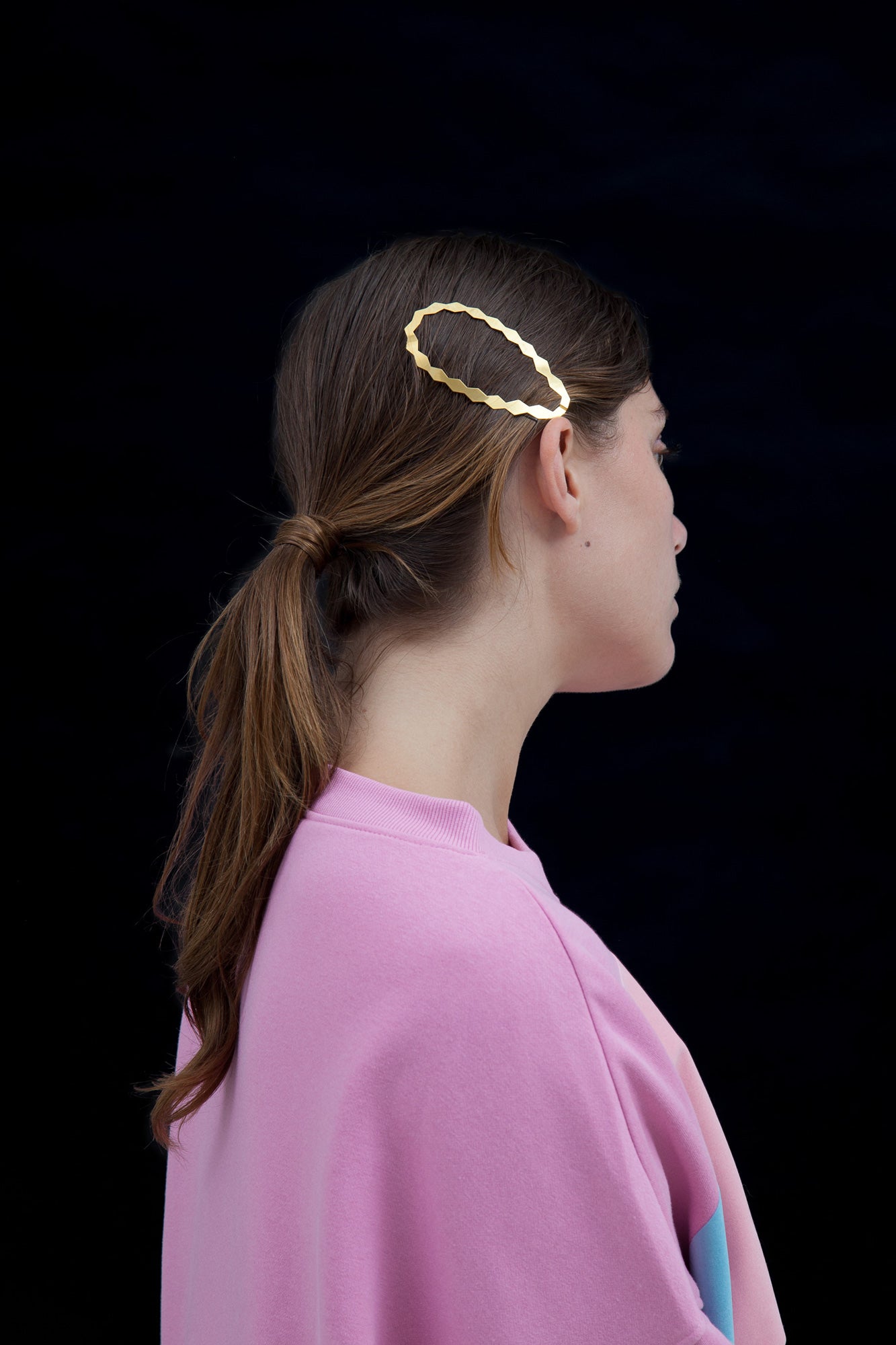 Model wearing a low wrapped ponytail with designer hair clip EVA in gold-plated as decorative accent 