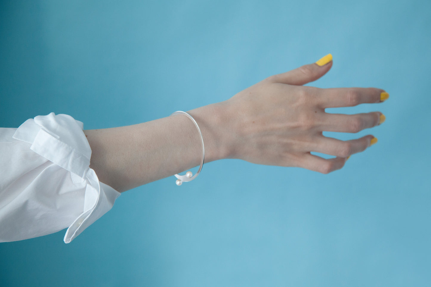 Close up of modern pearl Designer bangle bracelet April by CLINQ. Mirror polished stainless steel with cultured freshwater pearls Available in Silver-tone and Gold-plated . Handmade in Germany