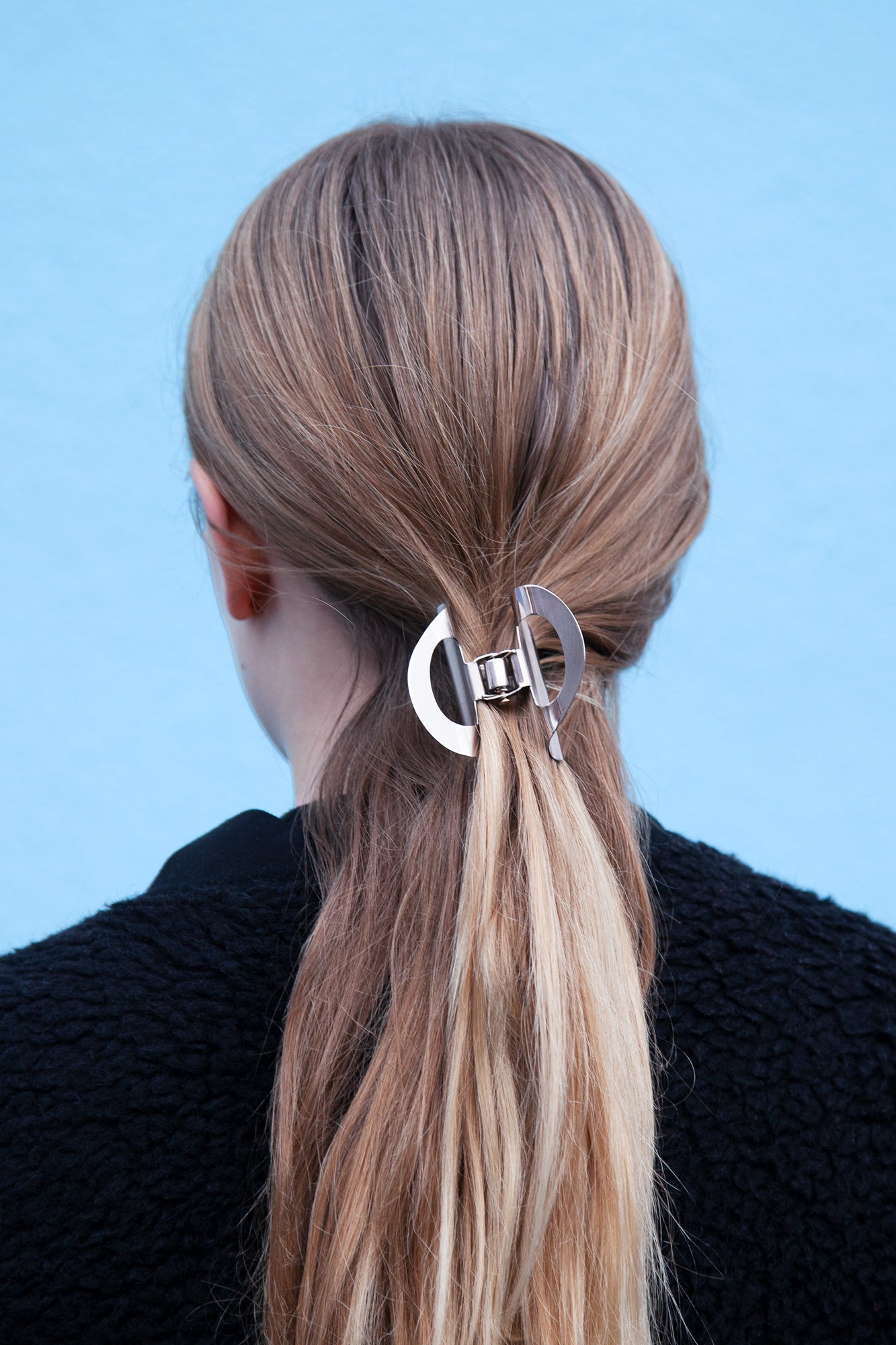 model wearing the sculpted claw clip SANA made from mirror polished stainless steel in silver-tone 