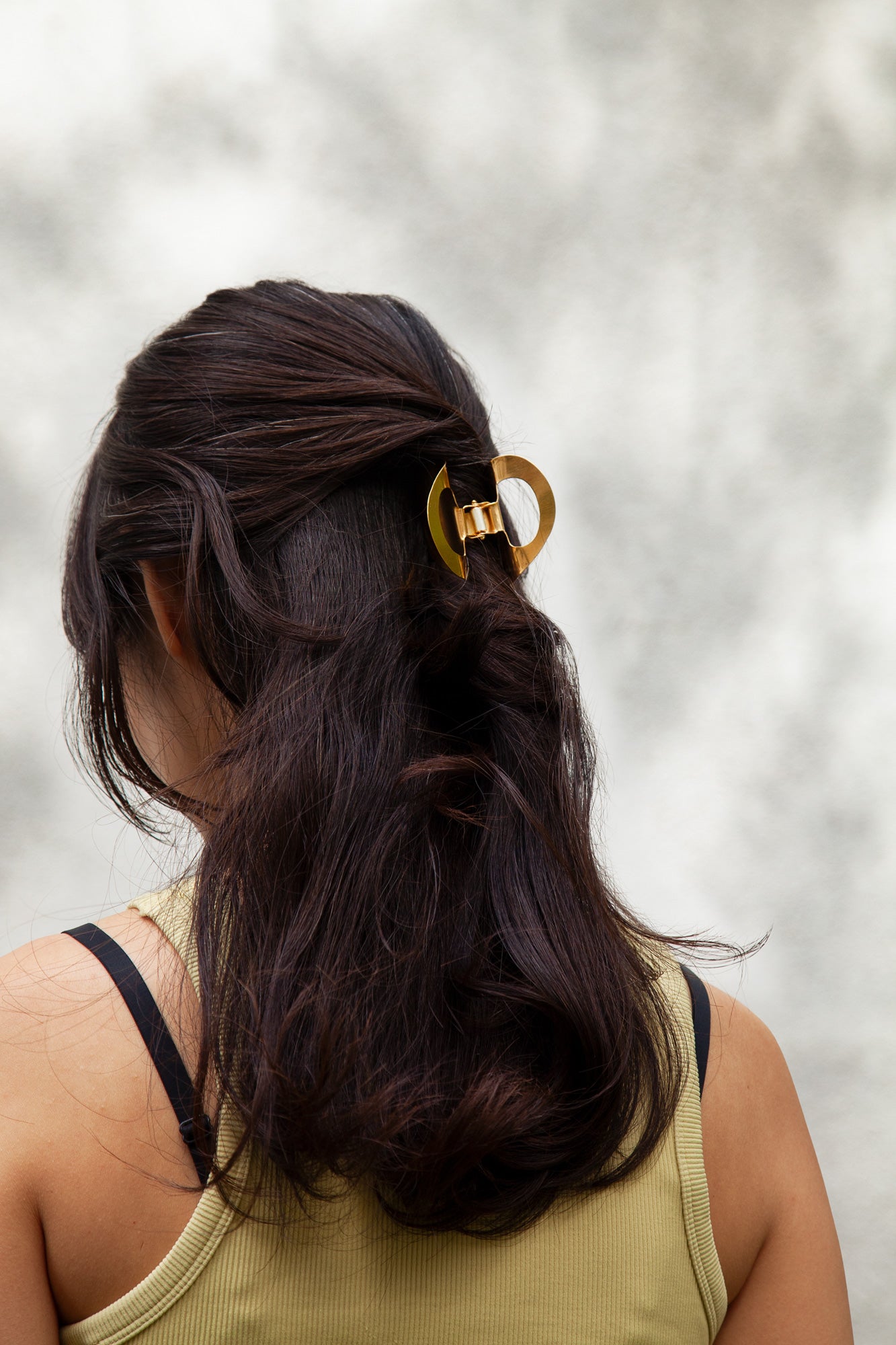 Model wearing the designer claw clip SANA made from mirror polished stainless steel in gold-plated