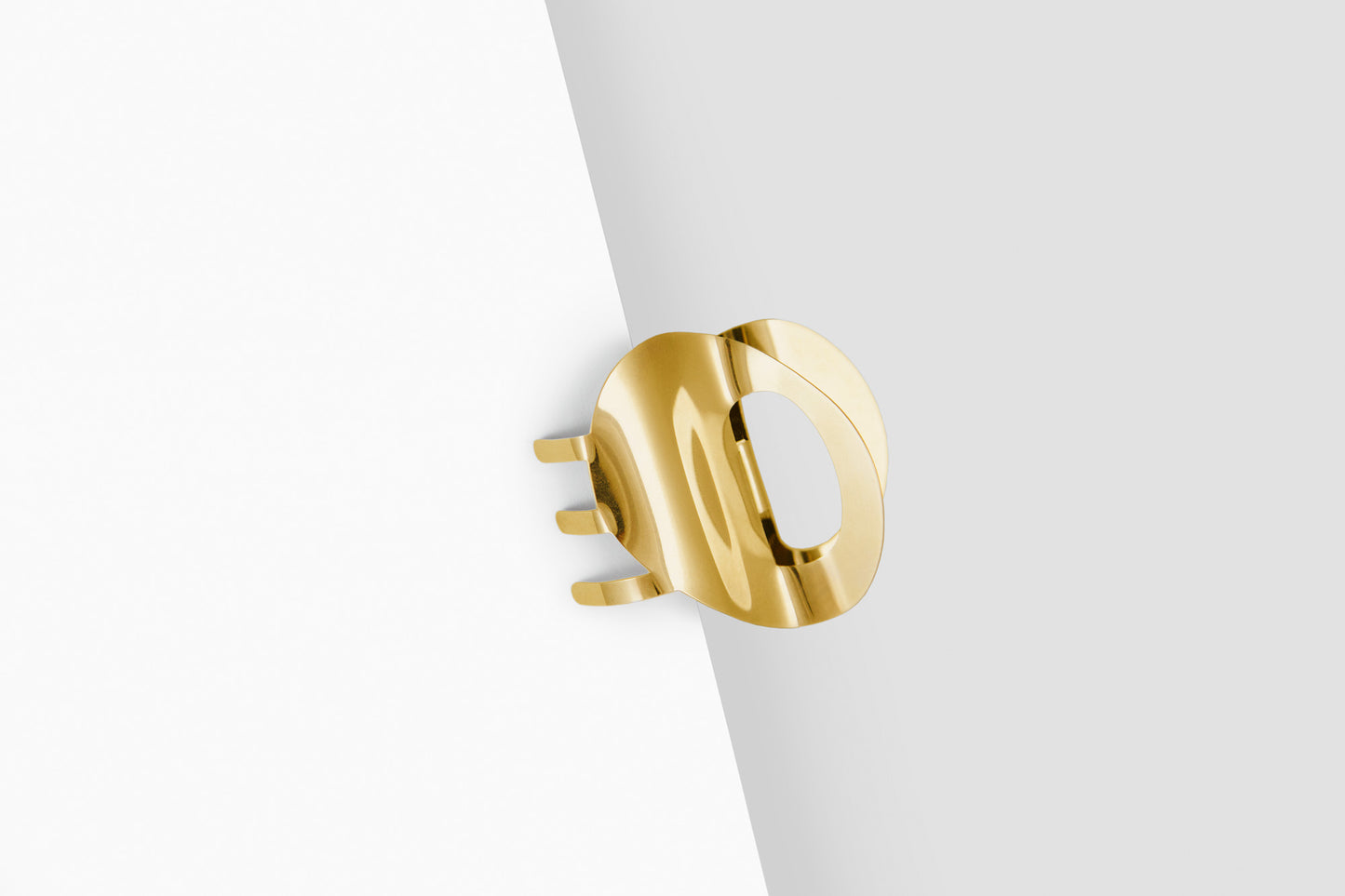 Product shot of the sculpted claw clip SANA clipped in, made from mirror polished stainless steel in gold-plated