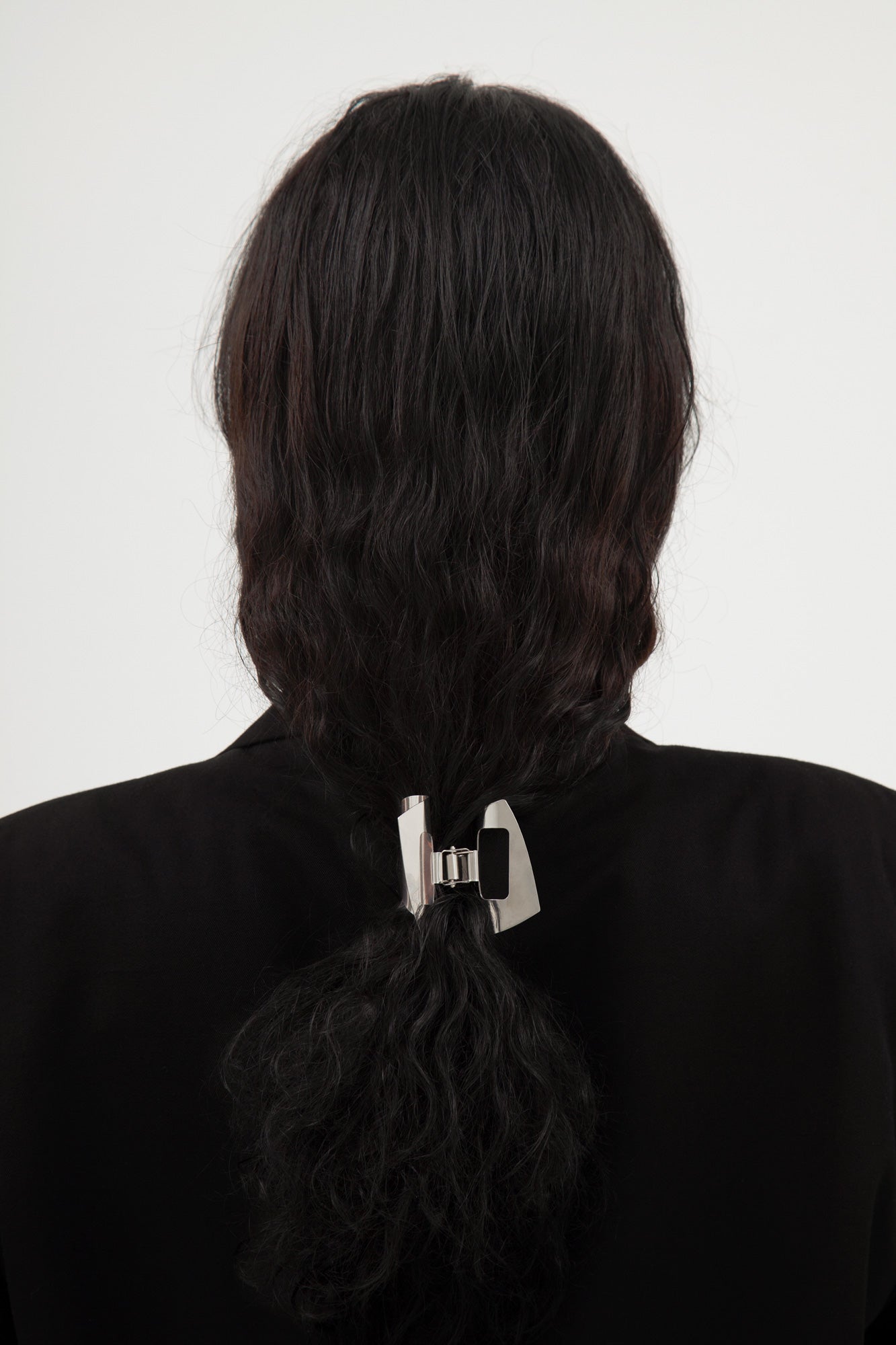 Person with black hair tied in a ponytail with designer stainless steel claw clip MIRA by CLINQ 