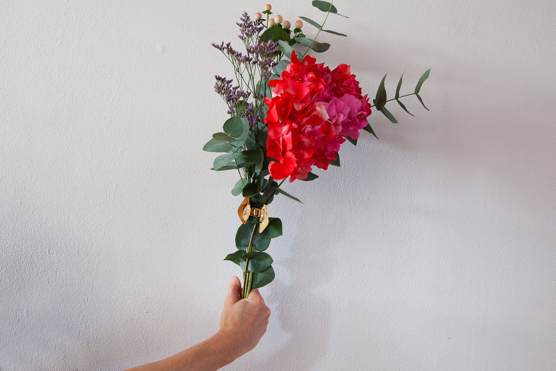 Bouquet of red and pink flowers hold together with a gold plated claw clip with rock crystal beads and freshwater pearl