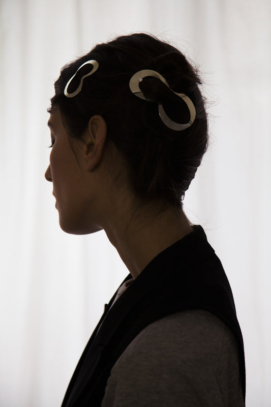 Side view of model wearing her hair in a neat updo secured with designer hair clips Clio and Lina by Clinq 