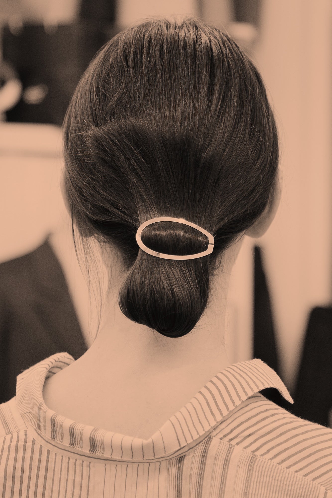 Back view of model wearing her hair in a folded low ponytail secured with designer hair clip Damia by Clinq 