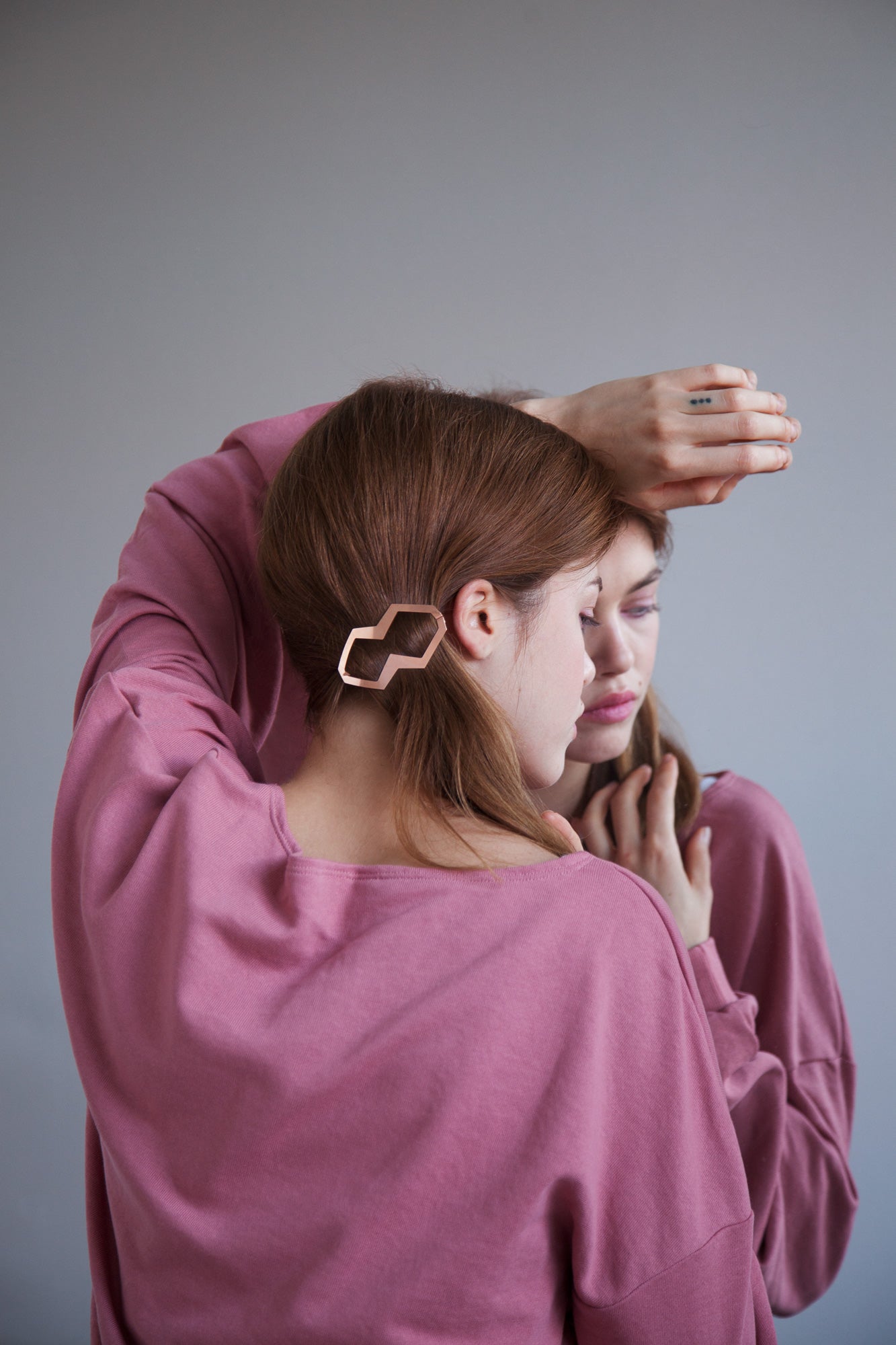 Model looking to the side wearing her hair in a low side ponytail accessorized with designer hair clips Bia and Dora in Roségold-plated 