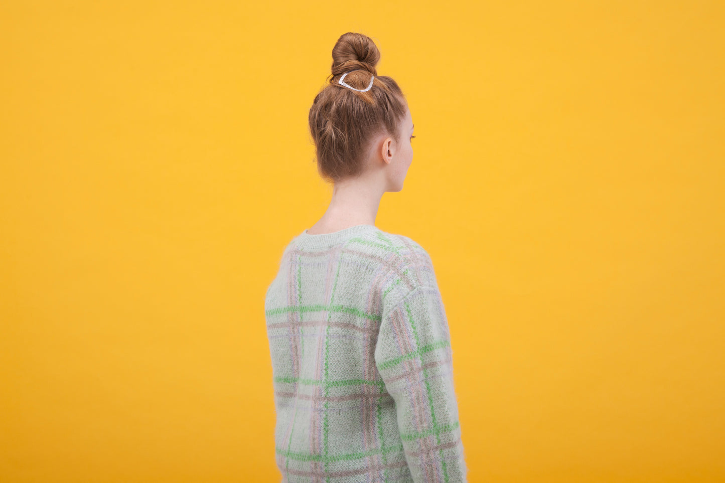 Side view of the model wearing a top knot hair style with the artistically shaped designer hair clip BARBARA by CLINQ