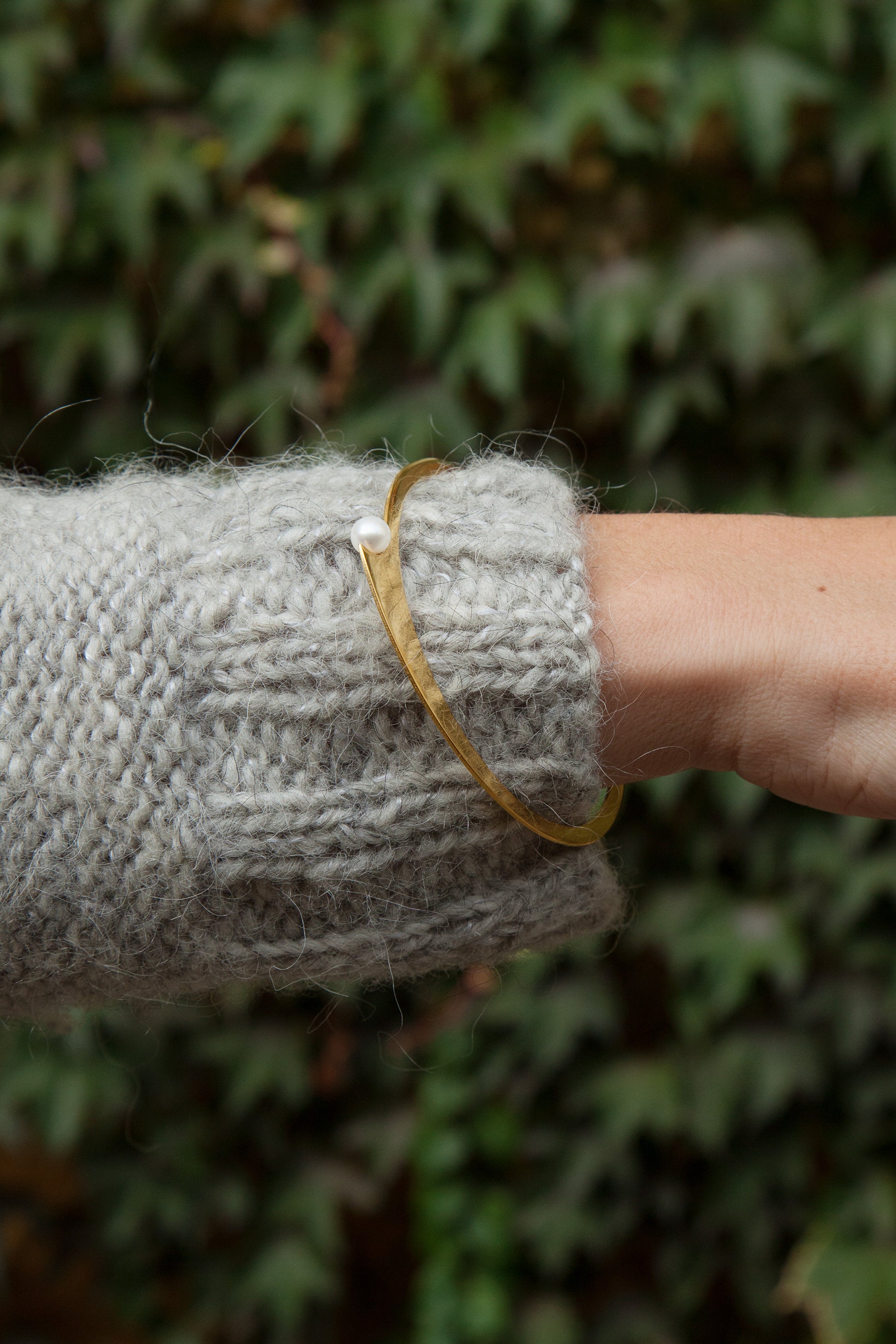 Close up of model wearing designer slip on bracelet Dahlia by Clinq in gold-plated