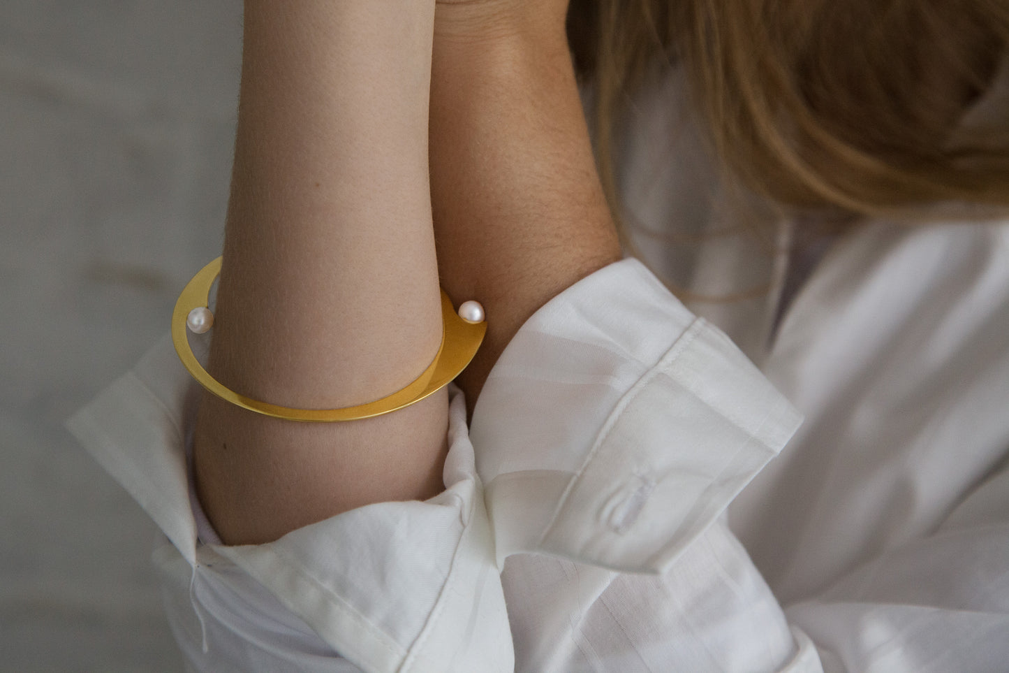 Close-up of the models arm wearing the designer bangle bracelet ELEA with freshwater pearly